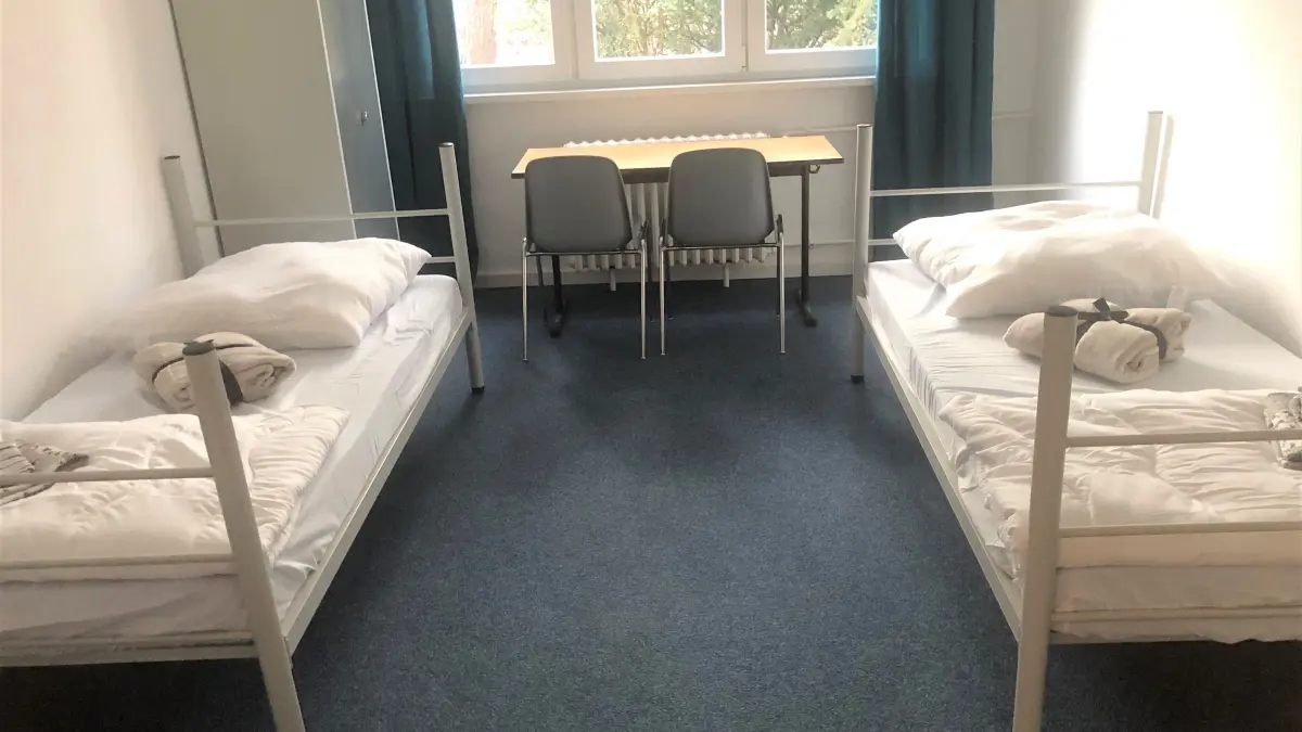 Blick in ein Doppelzimmer: Die Einrichtung im Haus am Stadtsee bei Eberswalde besteht aus zwei Betten, zwei Stühlen, einem Tisch und einem Schrank. Auch der einstige Gastraum wurde mit Trockenwänden unterteilt, um Platz zu schaffen. Der frühere Saal hingegen wird aus Kostengründen nicht hergerichtet und dient nur für Lagerzwecke.