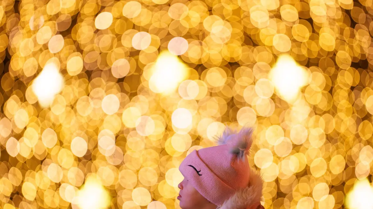 Weihnachten in Rumänien: 14.12.2024, Rumänien, Bukarest: Ein Kind betrachtet Lichtinstallationen, während es auf den Schultern eines Erwachsenen auf einem Weihnachtsmarkt in Bukarest getragen wird. Foto: Andreea Alexandru/AP/dpa +++ dpa-Bildfunk +++