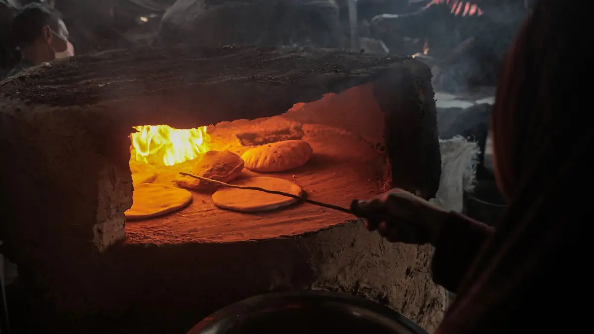 Nahostkonflikt - Palästinensische Gebiete: 15.12.2024, Palästinensische Gebiete, Deir al-Balah: Palästinenser backen Brot mit einem Lehmofen in einem beschädigten Haus in Deir al-Balah im zentralen Gazastreifen. Foto: Rizek Abdeljawad/XinHua/dpa +++ dpa-Bildfunk +++