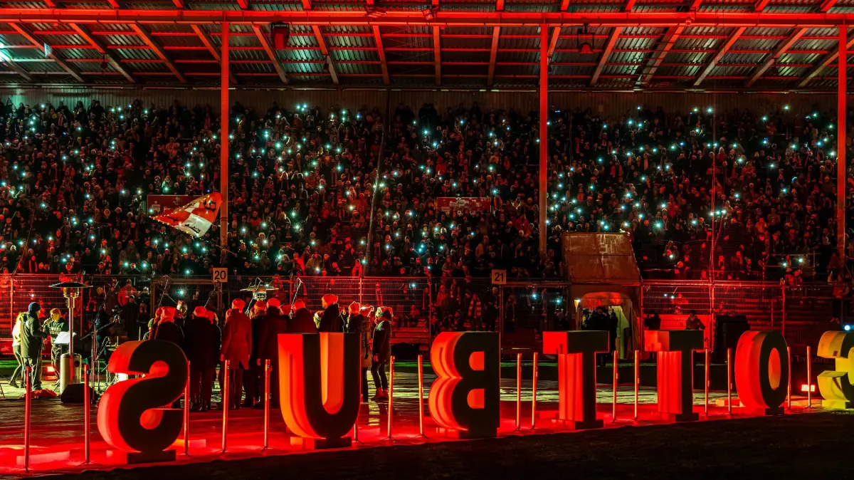 Weihnachtssingen beim FC Energie Cottbus: Mitglieder des PopKon Cheores aus Cottbus singen gemeinsam mit Alexander Knappe vor der Nordwand im LEAG Energie Stadion beim Weihnachtssingen des FC Energie Cottbus.