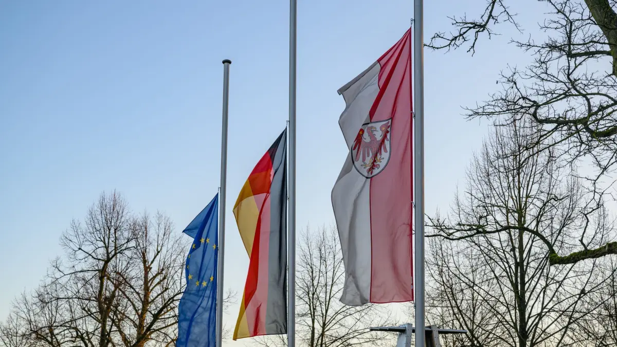 Trauerbeflaggung zum Gedenken an getöteten Polizisten: 08.01.2025, Brandenburg, Frankfurt (Oder): Die Flaggen der Europäischen Union (l-r), Deutschland und dem Land Brandenburg wehen anlässlich des Todes eines sächsischen Polizisten im Dienst vor dem Polizeipräsidium Ost auf Halbmast. Ein Polizist aus Dresden ist am 07. Januar 2025 in Lauchhammer in Brandenburg bei einer Fahndung nach Autodieben erfasst und getötet worden. Foto: Patrick Pleul/dpa +++ dpa-Bildfunk +++
