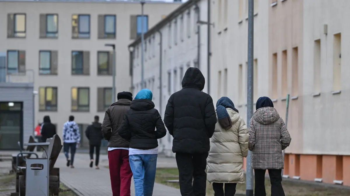 Unterkunft für Asylbewerber: ARCHIV - 14.12.2023, Brandenburg, Eisenhüttenstadt: Migranten gehen über das Gelände der Zentralen Erstaufnahmeeinrichtung für Asylbewerber (ZABH) des Landes Brandenburg in Eisenhüttenstadt. (zu dpa: «Rund 13.500 Asylanträge in Berlin – 5.880 in Brandenburg») Foto: Patrick Pleul/dpa +++ dpa-Bildfunk +++