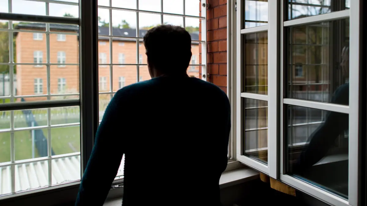Maßregelvollzug: ARCHIV - 29.04.2016, Brandenburg, Eberswalde: Ein Straftäter steht vor einem vergitterten Fenster in einer Klinik für Forensische Psychiatrie. (zu dpa: «Maßregelvollzug in Brandenburg stark überbelegt») Foto: Patrick Pleul/dpa-Zentralbild/dpa +++ dpa-Bildfunk +++