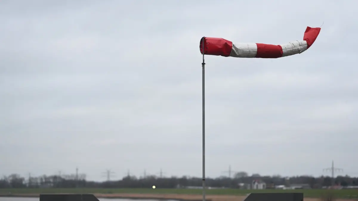 ARCHIV - 30.12.2024, Niedersachsen, Leer: Ein Windbeutel steht waagerecht im Wind auf der Jann-Berghaus-Brücke in Leer Ostfriesland. Der Deutsche Wetterdienst (DWD) hat eine Warnung zu schweren Sturmböen auf dem Brocken und Windböen an der Küste ausgegeben. (zu dpa: «Stürmisches Wetter in Thüringen») Foto: Lars Penning/dpa +++ dpa-Bildfunk +++