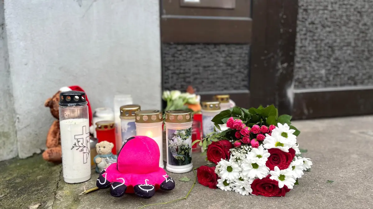 Nach dem Brand im Pflaumenweg in Frankfurt (Oder) wurden Blumen, Kerzen und Plüschtiere für die Toten vor dem Haus abgelegt. Die Polizei teilt erste Erkenntnisse über sie mit.
