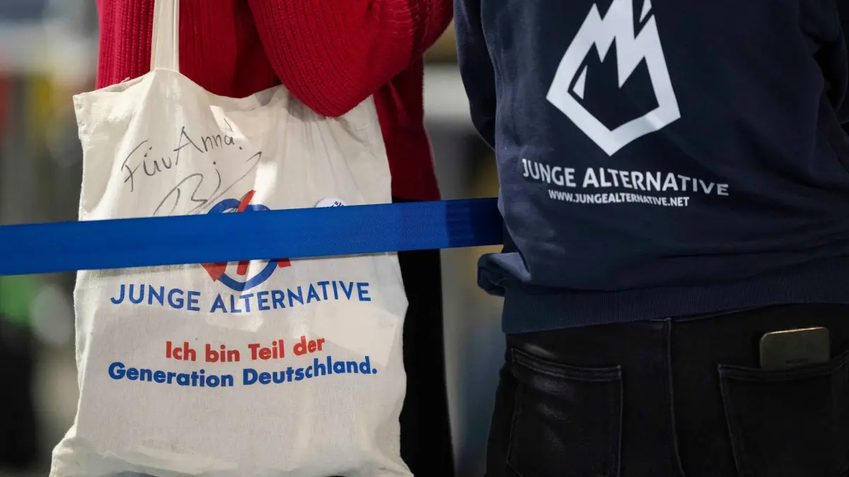 Die Junge Alternative löst sich auf.: ARCHIV - 12.01.2025, Sachsen, Riesa: Teilnehmer des AfD-Bundesparteitags in Riesa mit einem Stoffbeutel bzw. Pullover mit dem Logo der AfD-Jugendorganisation «Junge Alternative» (JA). (zu dpa: «Junge Alternative löst sich auf») Foto: Sebastian Kahnert/dpa +++ dpa-Bildfunk +++