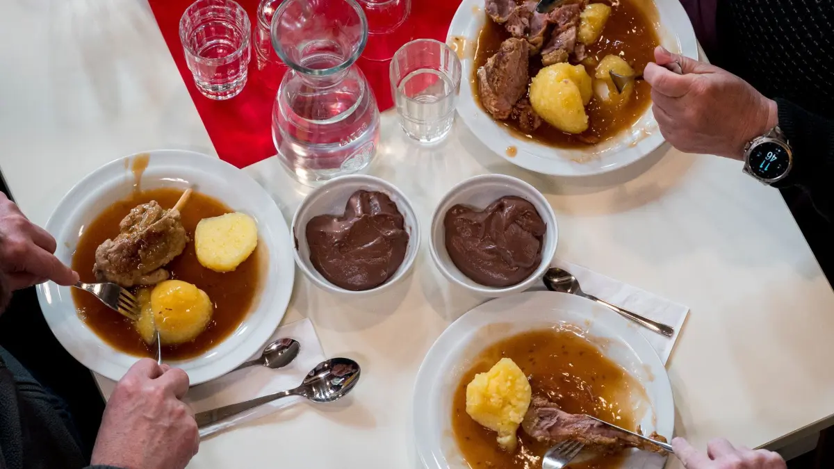 „Vesperkirchen“ in Bayern öffnen ihre Türen: 02.02.2025, Bayern, Nürnberg: Drei Teller mit kleinen Schweinshaxen mit Klößen stehen auf einem Tisch und werden von den Gästen der Vesperkirche gegessen. Der Diakonieverein Nürnberg-Lichtenhof und die evangelisch-lutherische Kirchengemeinde Nürnberg eröffnen zum 10. Mal die “Vesperkirche" mit einem Gottesdienst und schaffen für alle Menschen einen Ort der Begegnung, an dem es Essen, Seelsorge, verschiedene Beratungen und Konzertabende gibt. Foto: Daniel Vogl/dpa +++ dpa-Bildfunk +++