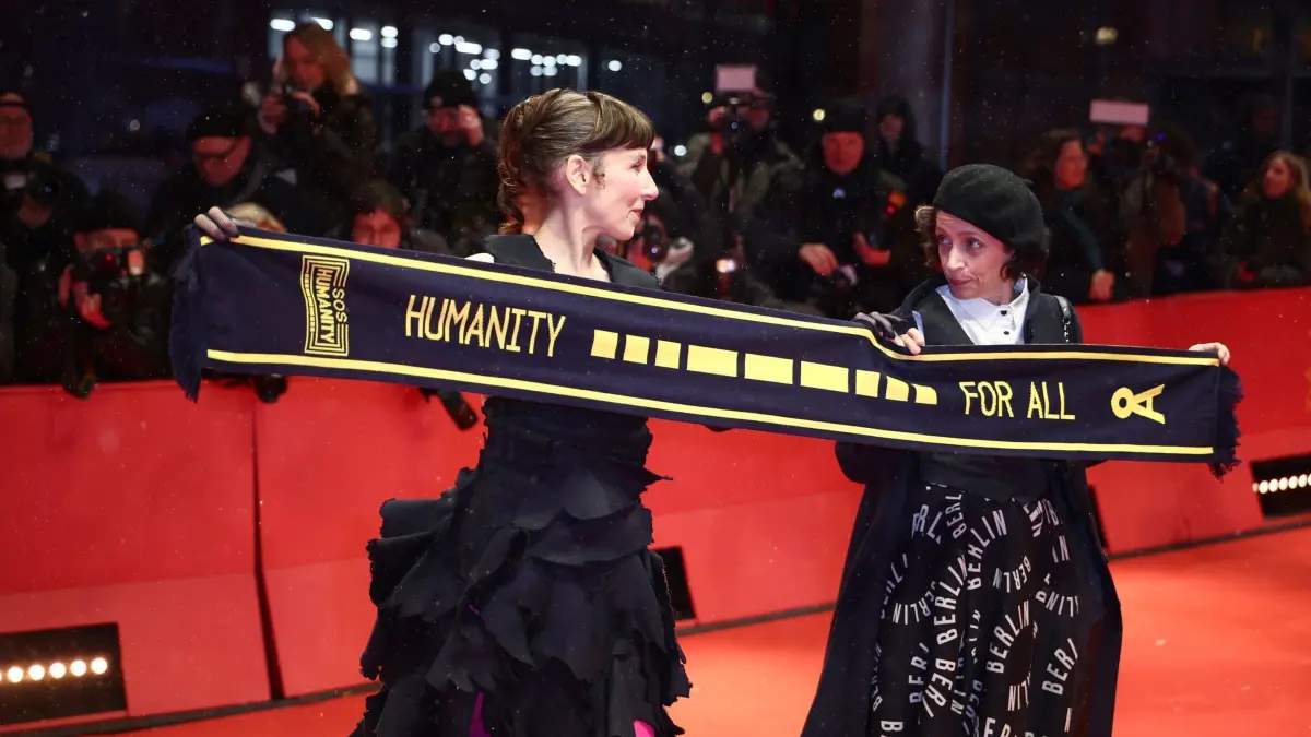 75. Berlinale - Eröffnung: 13.02.2025, Berlin: Die Schauspielerinnen Meret Becker und Anna Thalbach stehen am Eröffnungsabend der Berlinale auf dem Roten Teppich und halten einen Schal mit der Aufschrift "Humanity for all" von SOS Humanity. Es wird der Film «Das Licht» gezeigt. Die 75. Internationalen Filmfestspiele Berlin finden vom 13. bis 23. Februar 2025 statt. Foto: Christoph Soeder/dpa +++ dpa-Bildfunk +++