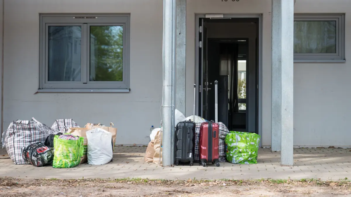 Das Saarland bringt Flüchtlinge etwa wie hier in Lebach unter.: ARCHIV - 20.04.2022, Saarland, Lebach: Gepäck steht vor einem Gebäude der Landesaufnahmestelle Lebach. (Archivfoto) (zu dpa: «2024 kamen weniger Asylsuchende und Flüchtlinge ins Saarland») Foto: Oliver Dietze/dpa +++ dpa-Bildfunk +++