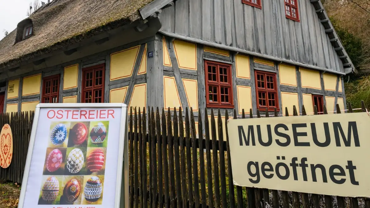 25 Jahre Ostereierausstellung im Strohhaus: 12.03.2025, Brandenburg, Neuzelle: Vor dem Strohhaus Neuzelle wirbt ein Aufsteller für die diesjährige Ostereierausstellung. Das Strohhaus Neuzelle beherbergt das Museum ländlicher Alltagskultur. Es besteht aus einem Fachwerkwohnhaus und Fachwerkstallgebäude mit Rohrdeckung und Roggenstrohfirst und wurde um 1780 erbaut. Seit nunmehr 25 Jahren findet hier eine Ostereierausstellung statt. Zu bewundern sind einige hundert reich verzierte, bemalte und bedruckte Hühner, Nandu- oder Straußeneier. Die zerbrechlichen Kunstwerke sind Leihgaben der Familie Keller aus Neuzelle und der Familie Krüger aus Ziltendorf. Foto: Patrick Pleul/dpa - Honorarfrei nur für Bezieher des Dienstes ZB-Funkregio Ost +++ ZB-FUNKREGIO OST +++