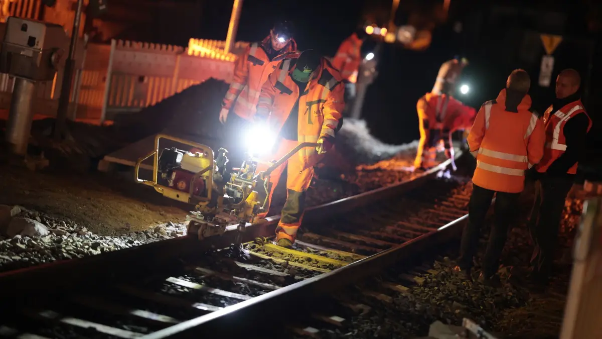Bauarbeiten mit Spezialmaschine bei den Harzer Schmalspurbahnen: 13.03.2025, Sachsen-Anhalt, Wernigerode: Mitarbeiter eines Gleisbaubetriebes arbeiten an einem Bahnübergang der Harzer Schmalspurbahnen GmbH in Wernigerode. Auf der Nachtbaustelle wird unter anderem der Schotterbelag unter den Bahnschwellen mit einer Spezialmaschine verdichtet. Die HSB unterhält auf ihrem Gleisnetz über 100 Bahnübergänge die nach und nach umgebaut und mit neuen Signalanlagen sowie Schranken ausgerüstet werden. Die Arbeiten an den Bahnübergangsstellen werden in den kommenden Tagen weiter fortgesetzt. Foto: Matthias Bein/dpa +++ dpa-Bildfunk +++