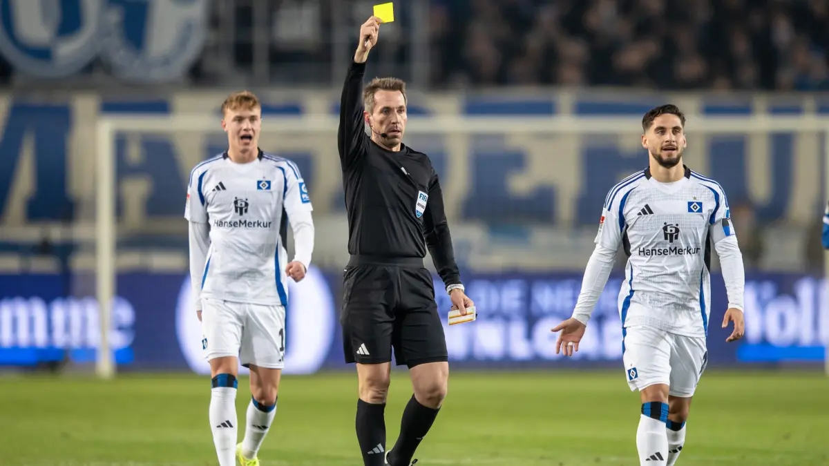 1. FC Magdeburg - Hamburger SV: 14.03.2025, Sachsen-Anhalt, Magdeburg: Fußball: 2. Bundesliga, 1. FC Magdeburg - Hamburger SV, 26. Spieltag, Avnet Arena. William Mikelbrencis von Hamburger SV erhält eine Gelbe Karte von Schiedsrichter Tobias Stieler (M). Foto: Andreas Gora/dpa - WICHTIGER HINWEIS: Gemäß den Vorgaben der DFL Deutsche Fußball Liga bzw. des DFB Deutscher Fußball-Bund ist es untersagt, in dem Stadion und/oder vom Spiel angefertigte Fotoaufnahmen in Form von Sequenzbildern und/oder videoähnlichen Fotostrecken zu verwerten bzw. verwerten zu lassen. +++ dpa-Bildfunk +++
