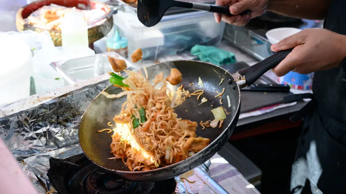 Thai-Streetfood-Markt in Berlin: ARCHIV - 15.09.2023, Berlin: Ein Mensch kocht in seiner mobilen Küche auf dem Thai-Streetfood-Markt im Preußenpark in Berlin-Wilmersdorf. Von Frühjahr bis Herbst wird im sogenannten Thaipark an vielen Ständen thailändisches Essen verkauft. (zu dpa: «Start des Thaimarkts im April in Sicht») Foto: Bernd von Jutrczenka/dpa +++ dpa-Bildfunk +++
