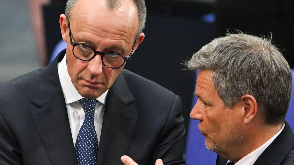 German Minister of Economics and Climate Protection and main candidate of Germany's Green party Robert Habeck (R) speeks with Friedrich Merz, the leader of Germany's Christian Democratic Union (CDU) during the constituent session of Germany's new Bundestag (lower house of parliament) on March 25, 2025 in Berlin. Germany's new parliament sits for the first time with a reduced headcount, fewer women and a record number of lawmakers from the far-right Alternative for Germany (AfD). (Photo by RALF HIRSCHBERGER / AFP)