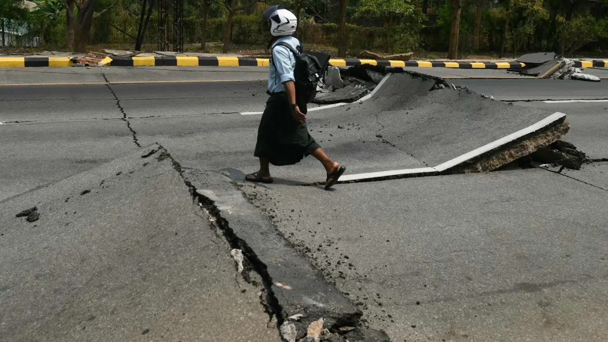 A man walks along a damaged road in Naypyidaw on March 28, 2025, after an earthquake in central Myanmar. A powerful earthquake hit Myanmar and neighbouring Thailand on March 28, turning a major hospital in the Burmese capital into a "mass casualty area" and trapping dozens of workers in an under-construction skyscraper in Bangkok. (Photo by Sai Aung MAIN / AFP)