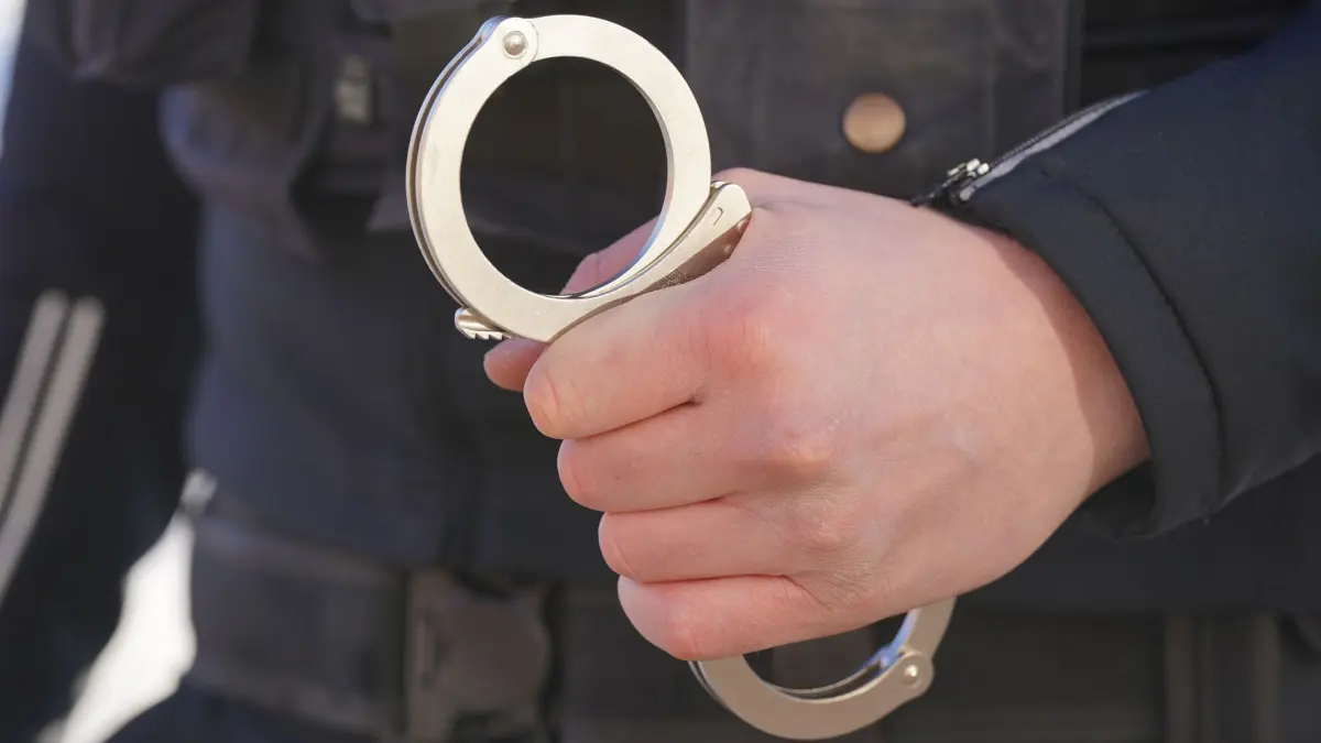 Polizei Handschellen - Symbolbild: ARCHIV - 18.01.2024, Mecklenburg-Vorpommern, Schwerin: ILLUSTRATION - Ein Polizist hält Handschellen in der Hand. (zu dpa: «Zwei Männer nach Schüssen auf Autobahn in U-Haft») Foto: Marcus Brandt/dpa +++ dpa-Bildfunk +++