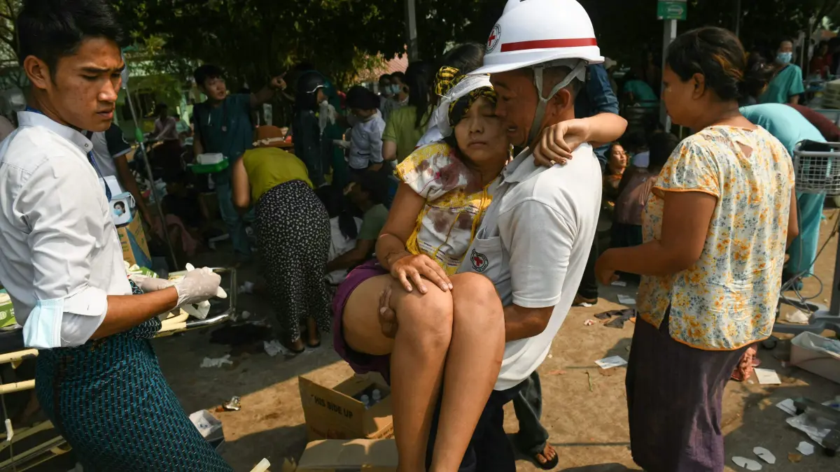 An earthquake survivor is carried as she waits to receive medical attention at a hospital in Naypyidaw on March 28, 2025, after an earthquake in central Myanmar. A powerful earthquake rocked central Myanmar on March 28, buckling roads in capital Naypyidaw, damaging buildings and forcing people to flee into the streets in neighbouring Thailand. (Photo by Sai Aung MAIN / AFP)