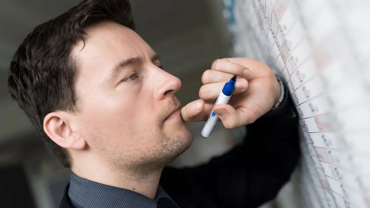 Mann trägt Termine in einen Wandkalender ein: ILLUSTRATION - Timeblocking: Aufgaben zu priorisieren und Zeit für die Selbstfürsorge einzubauen, kann den Druck nehmen, alles perfekt machen zu müssen. (zu dpa: «ADHS bei Erwachsenen: 3 konkrete Praxistipps von Fachleuten») Foto: Alexander Heinl/dpa-mag - Honorarfrei nur für Bezieher des Dienstes dpa-Magazin +++ dpa-Magazin +++