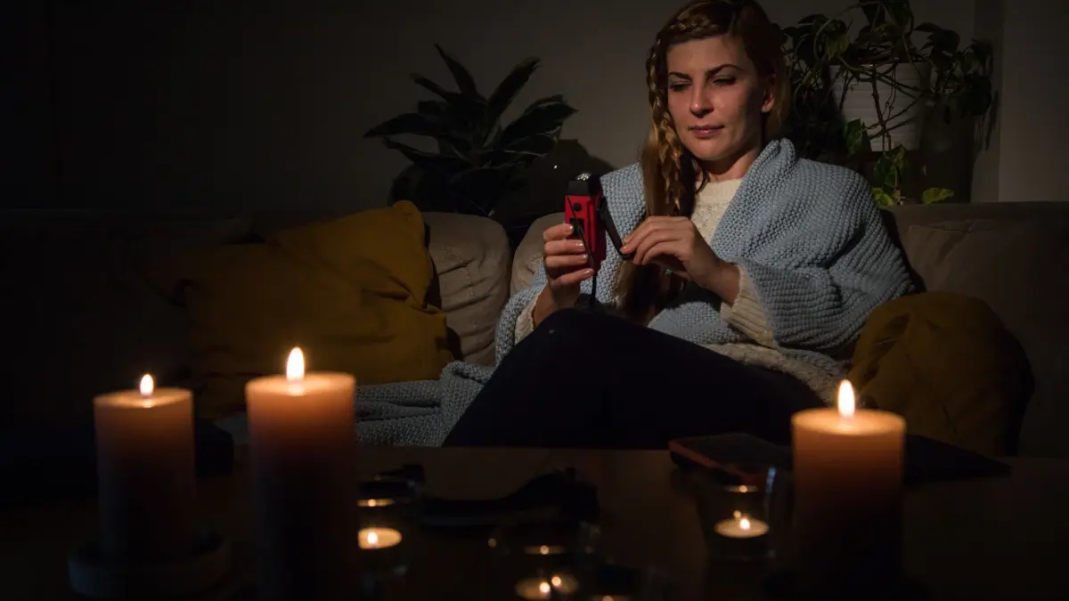 Frau hält bei Stromausfall ein Notfallradio in der Hand: ILLUSTRATION - Über ein batteriebetriebenes Radio können Notfallinformationen empfangen werden. (zu dpa: «Stromausfall: So bereiten Sie sich darauf vor») Foto: Christin Klose/dpa-tmn - Honorarfrei nur für Bezieher des dpa-Themendienstes +++ dpa-Themendienst +++