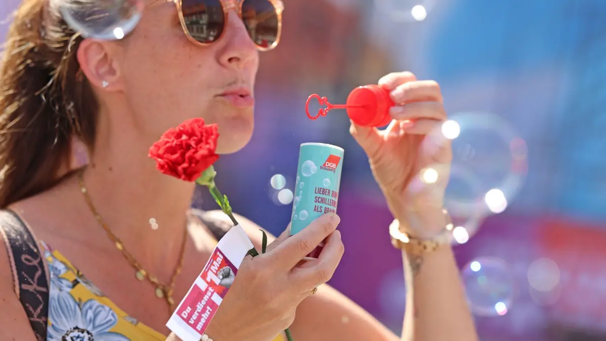 Tag der Arbeit - Wernigerode: 01.05.2025, Sachsen-Anhalt, Wernigerode: Die Teilnehmerin einer Kundgebung zum 1. Mai trägt eine rote Nelke. Mit Forderungen nach guten Arbeitsbedingungen, fairen Löhnen und einem stabilen Rentenniveau wollen die Gewerkschaften in diesem Jahr am 1. Mai auf die Straße gehen. Foto: Matthias Bein/dpa +++ dpa-Bildfunk +++