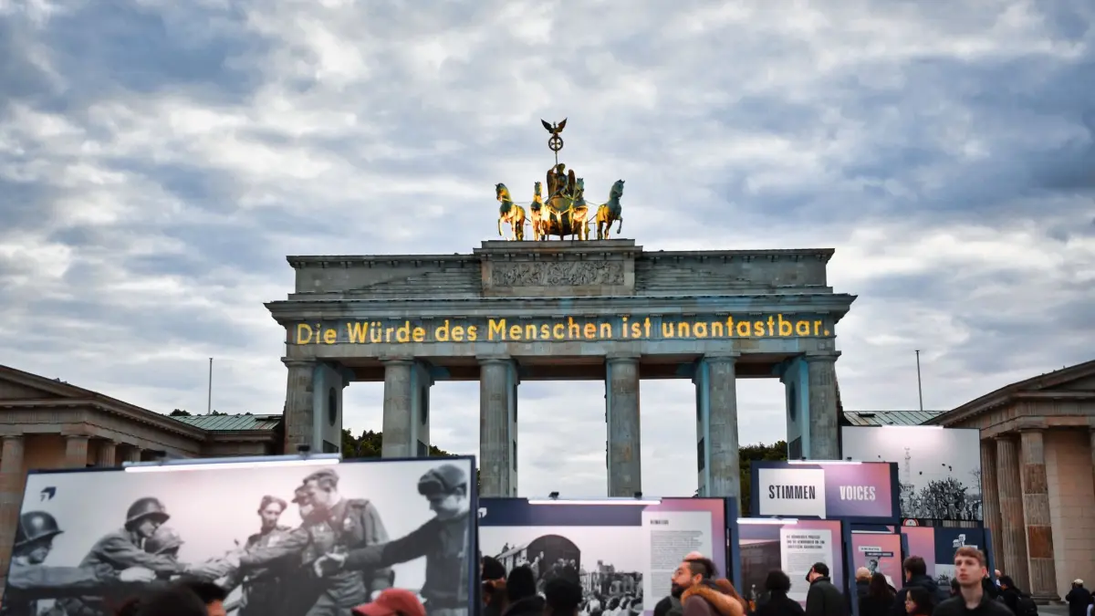 80. Jahrestag Ende Zweiter Weltkrieg - Berlin: 08.05.2025, Berlin: Die Würde des Menschen ist unantastbar steht auf dem Brandenburger Tor bei einer Lichtprojektion zum Jahrestag des Ende des Zweiten Weltkriegs. Am 8. Mai 1945 endete nach der Unterzeichnung der bedingungslosen Kapitulation Deutschlands am Tag zuvor der Zweite Weltkrieg in Europa. Foto: Paul Zinken/dpa - ACHTUNG: Nur zur redaktionellen Verwendung im Zusammenhang mit der aktuellen Berichterstattung +++ dpa-Bildfunk +++