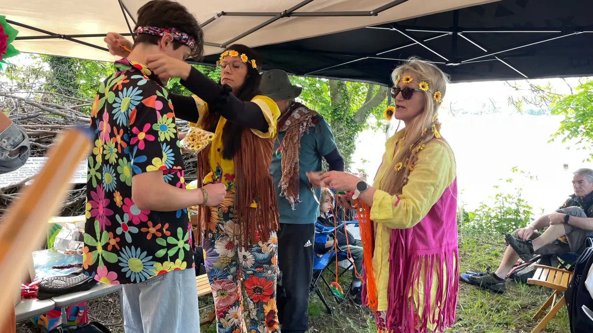 Das Flower Power Team trägt Halsketten mit Peacezeichen.