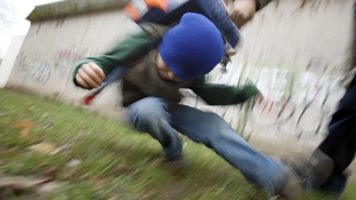Schüler drückt auf dem Schulhof einen anderen zu Boden: ILLUSTRATION - Ein Großteil der Gewalttaten von Kindern entsteht relativ spontan aus einer Streitsituation heraus. (zu dpa: «Gewalt bei Kindern: Wie Sie als Eltern vorbeugen können») Foto: Oliver Berg/dpa/dpa-tmn - Honorarfrei nur für Bezieher des dpa-Themendienstes +++ dpa-Themendienst +++