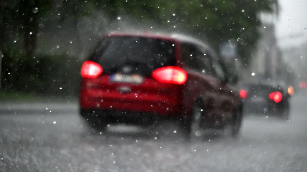 Ein Auto fährt durch einen Hagelschauer: ARCHIV - Vorsicht unterwegs: Bei Hagel Tempo drosseln und Warnblinker nutzen. (zu dpa: «Was schützt vor Hagel am Auto und zahlt bei einem Schaden?») Foto: Federico Gambarini/dpa-mag - Honorarfrei nur für Bezieher des Dienstes dpa-Magazin +++ dpa-Magazin +++