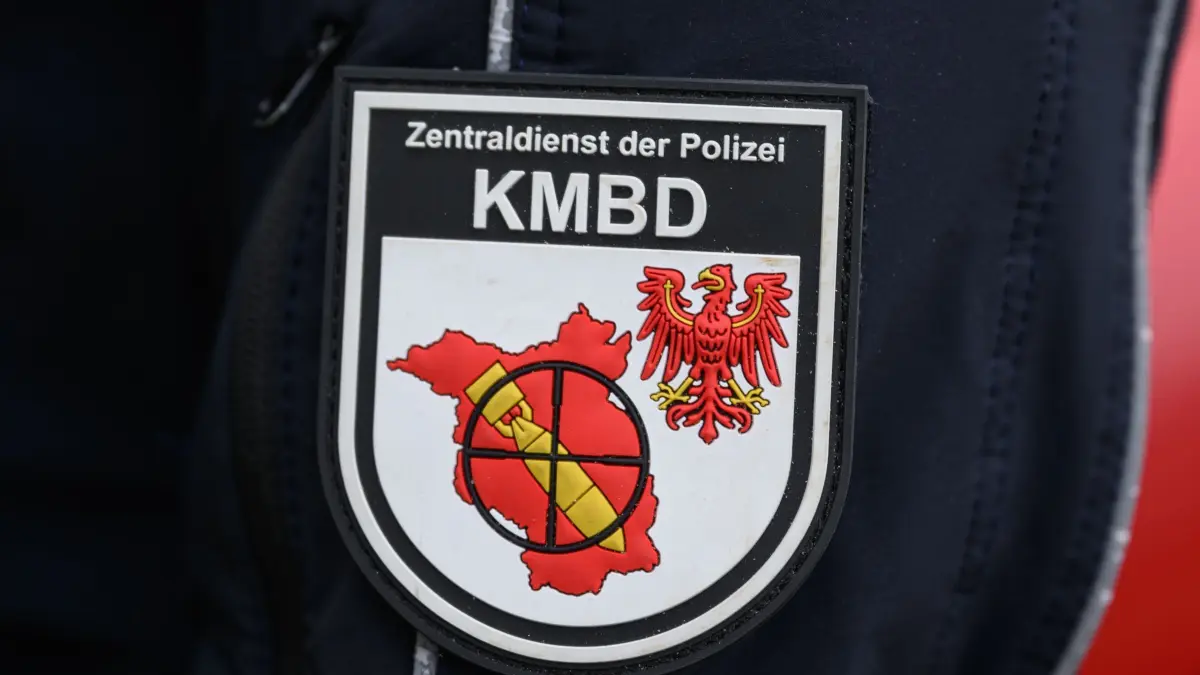 Kampfmittelbeseitigungsdienst: ARCHIV - 02.04.2025, Brandenburg, Frankfurt (Oder): Das Logo vom Kampfmittelbeseitigungsdienst (KMBD) der Polizei an der Jacke eines Sprengmeisters bei der Einsatzbesprechung vor Entschärfung einer Weltkriegsbombe in Frankfurt (Oder). (zu dpa: «Kriegsmunition in Lübbenau gesprengt») Foto: Patrick Pleul/dpa +++ dpa-Bildfunk +++