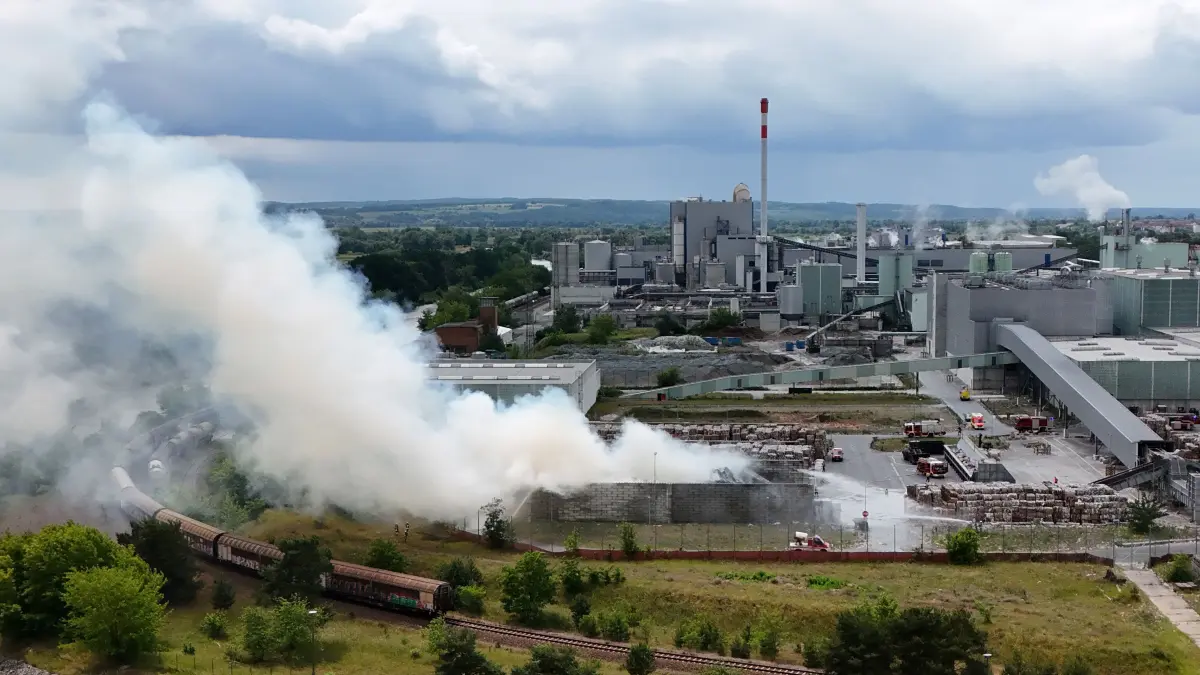 Die stark vergrößerte Drohnenaufnahme zeigt aus Richtung Hafen die Löscharbeiten auf dem Werkgelände des Papierhersteller Leipa.
