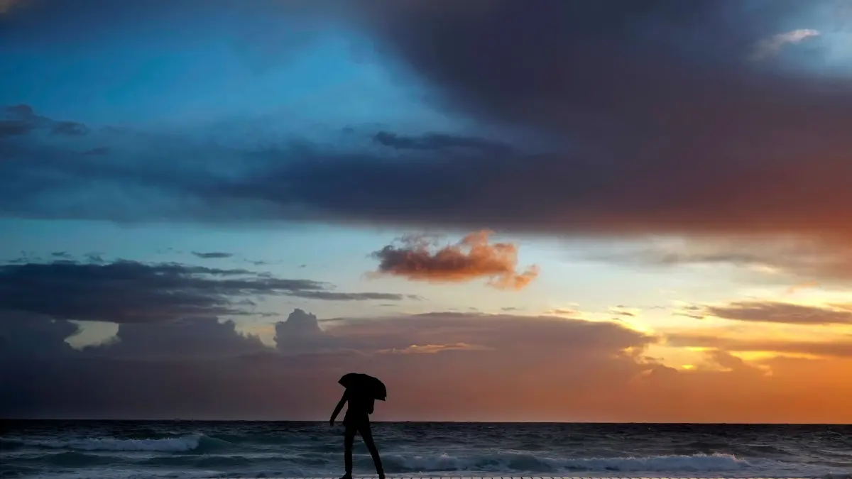 Ein Mann geht während einem Sonnenuntergang am 31.12.2017 am Strand in Ayia Napa (Zypern) spazieren. Foto: Petros Karadjias/AP/dpa +++ dpa-Bildfunk +++