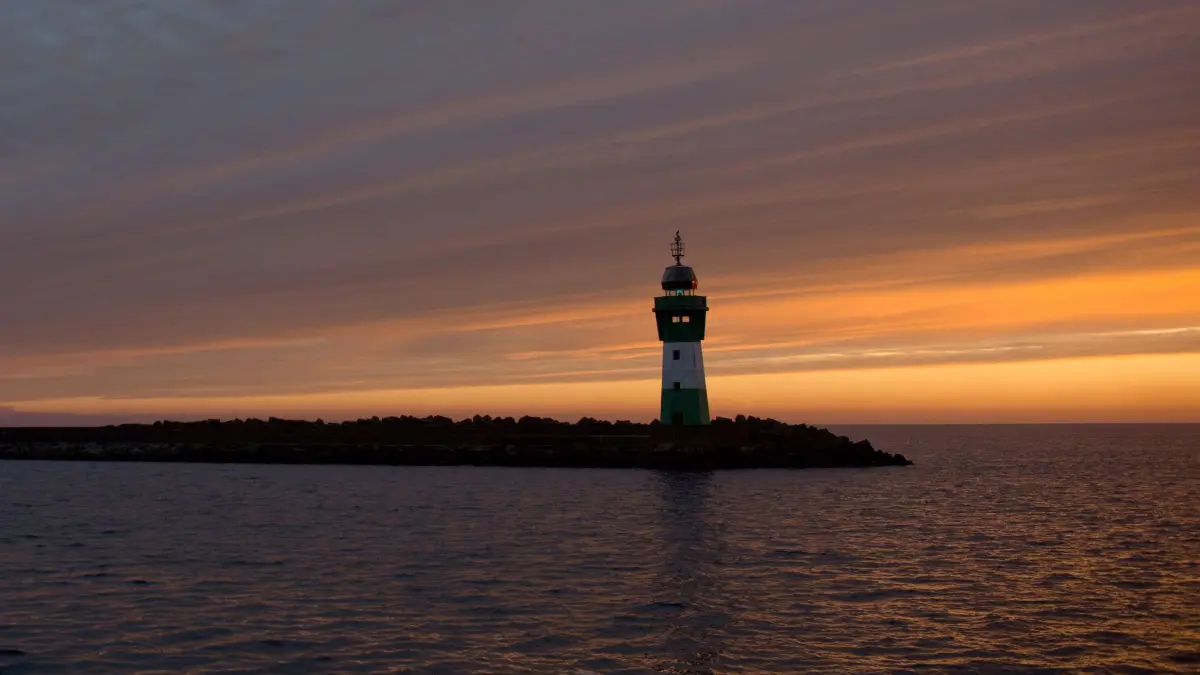 Die aufgehende Sonne über der Insel Rügen taucht am 20.12.2017 den Himmel über Leuchtturm in der Hafeneinfahrt von Mukran (Mecklenburg-Vorpommern) in ein warmes Licht. Für die nächsten Tage sagen die Meteorologen wechselhaftes Wetter für die Küstenregion vorher. Foto: Stefan Sauer/dpa-Zentralbild/dpa ++ +++ dpa-Bildfunk +++