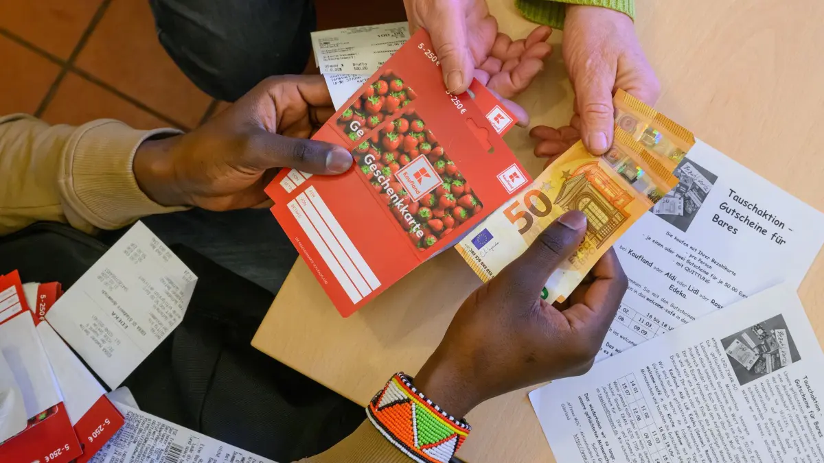 Bezahlkarte: Geflüchtete tauschen Gutscheine gegen Bargeld: ARCHIV - 11.03.2025, Brandenburg, Seelow: Im Willkommens-Café für Geflüchtete in einem Raum der Kirche von Seelow tauscht ein junger Mann aus Afrika Gutscheine gegen Bargeld. (zu dpa: «Bezahlkarte für Geflüchtete: Tauschstationen in ganz Bayern») Foto: Patrick Pleul/dpa +++ dpa-Bildfunk +++