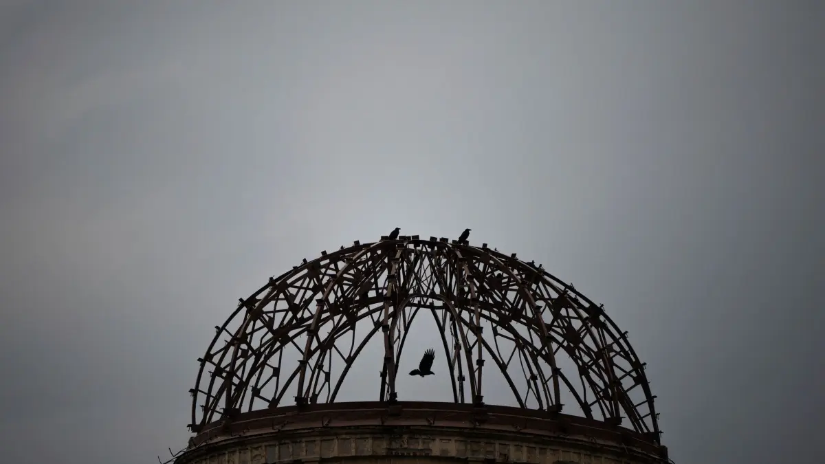 Vor dem 80. Jahrestag des Atombombenabwurfs auf Hiroshima: 04.08.2025, Japan, Hiroshima: Eine Krähe fliegt an der Atombombenkuppel vorbei. Japan gedenkt am 06. August des 80. Jahrestages des US-Atombombenabwurfs im Zweiten Weltkrieg. Foto: Louise Delmotte/AP/dpa +++ dpa-Bildfunk +++