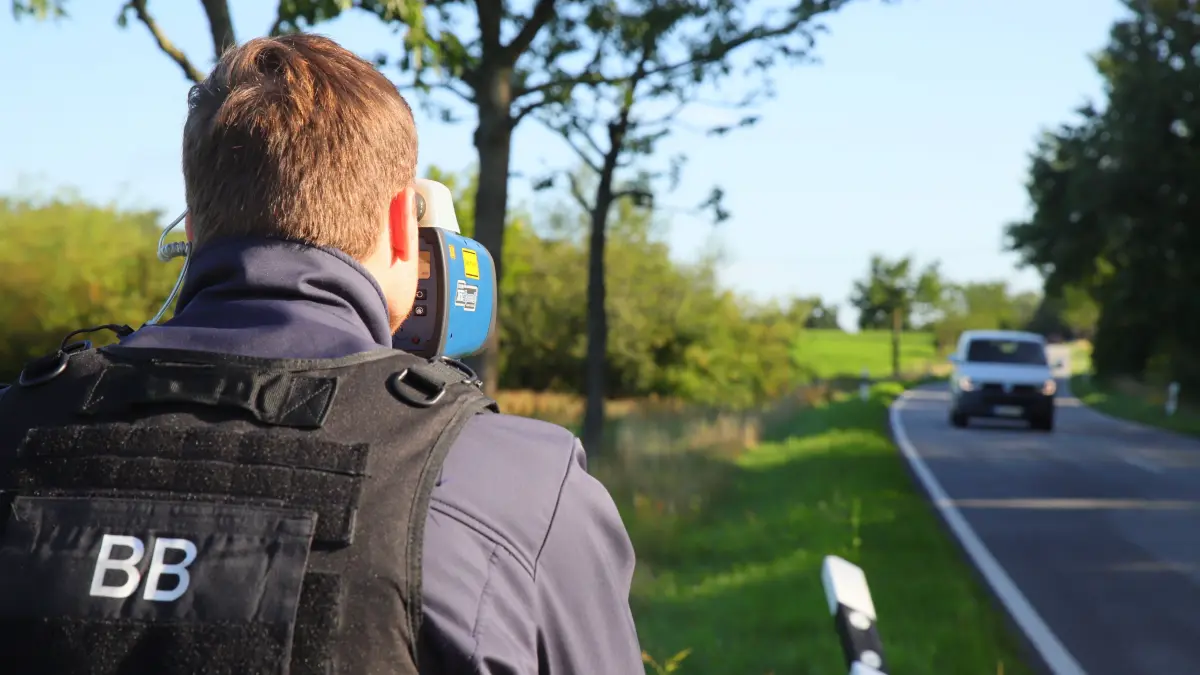 Blitzermarathon 2025: Mit einem Lasergerät misst ein Polizeibeamter an der B168 bei Fürstenwalde die Geschwindigkeit.