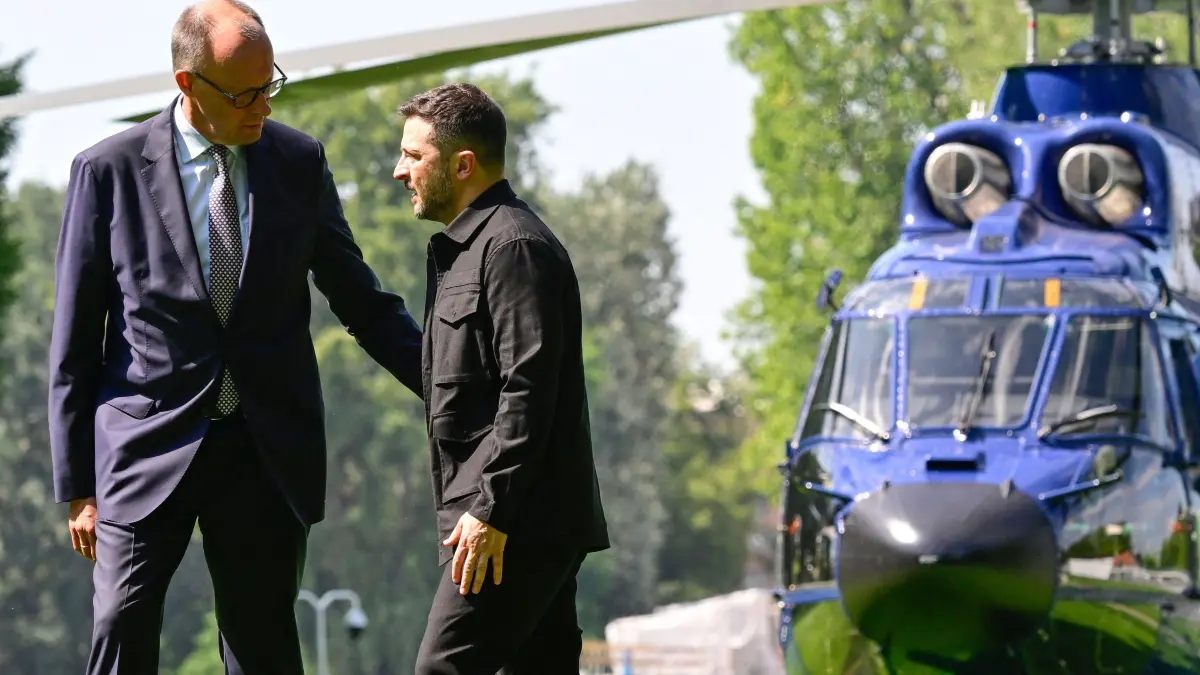 Ukrainian President Volodymyr Zelensky (R) walks next to German Chancellor Friedrich Merz upon arrival in the garden of the chancellery in Berlin to join a video conference of European leaders with the US President on the Ukraine war ahead of the summit between the US and Russian leaders, on August 13, 2025. European leaders will hold online talks with US President Donald Trump, hoping to convince him to respect Ukraine's interests when he discusses the war with Putin in Alaska on Friday. (Photo by John MACDOUGALL / POOL / AFP)