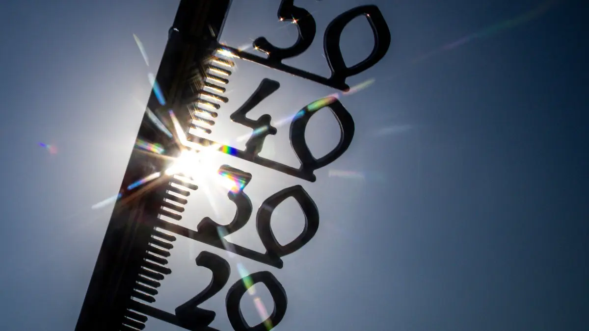 Sommerwetter - Schwerin: 14.08.2025, Mecklenburg-Vorpommern, Schwerin: Vor einem wolkenlosen blauen Himmel zeigt ein Außenthermometer in einem Garten bereits am Vormittag über 30 Grad Lufttemperatur an. Auch für die kommenden Tage hat der Deutsche Wetterdienst (DWD) für Norddeutschland weiterhin Sonne und Temperaturen bis zu 38 Grad angekündigt. Foto: Jens Büttner/dpa +++ dpa-Bildfunk +++