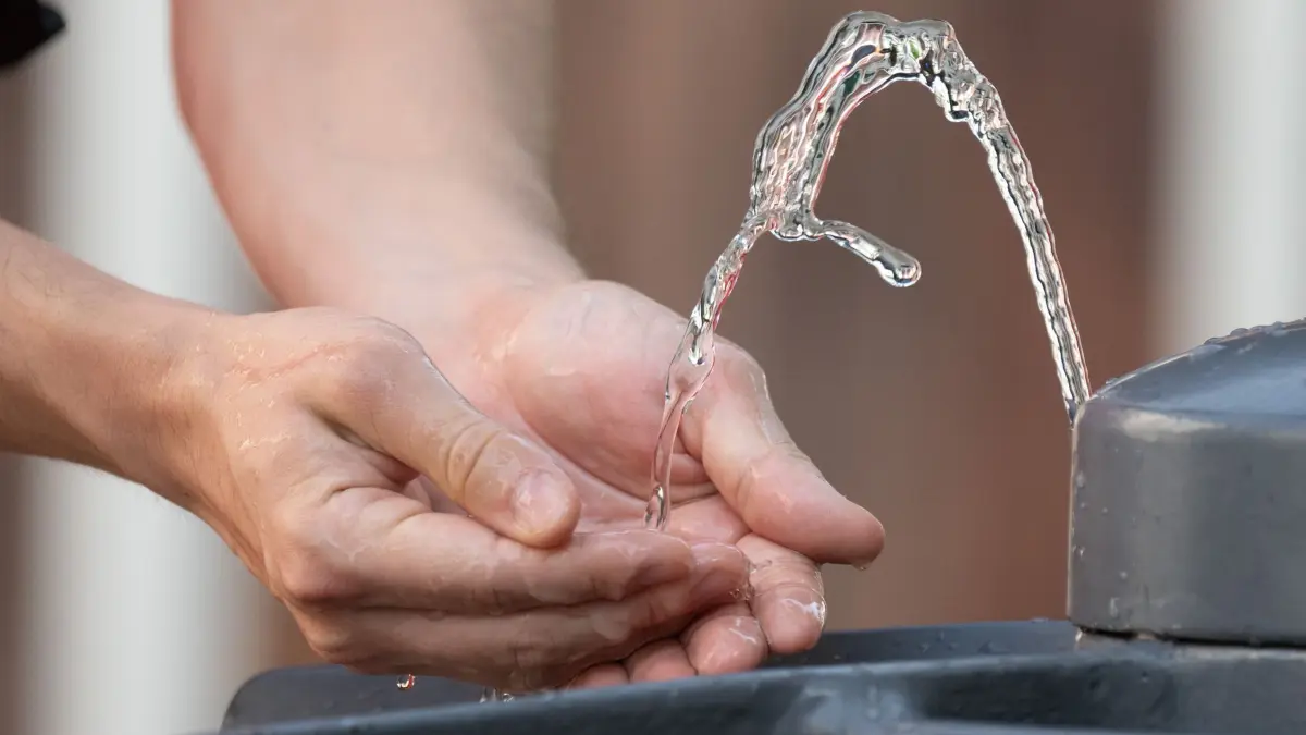 Sommerwetter - Dresden: 15.08.2025, Sachsen, Dresden: Ein Mann kühlt bei heißem Sommerwetter seine Hände an einem Trinkwasserbrunnen. Foto: Sebastian Kahnert/dpa +++ dpa-Bildfunk +++