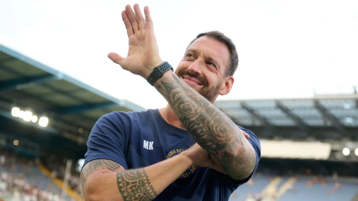 Arminia Bielefeld - Werder Bremen: 15.08.2025, Nordrhein-Westfalen, Bielefeld: Fußball, DFB-Pokal, Arminia Bielefeld - Werder Bremen, 1. Runde, Schüco Arena. Trainer Mitch Kniat (Arminia Bielefeld) winkt vor dem Spiel zur Tribüne. Foto: Bernd Thissen/dpa - WICHTIGER HINWEIS: Gemäß den Vorgaben der DFL Deutsche Fußball Liga bzw. des DFB Deutscher Fußball-Bund ist es untersagt, in dem Stadion und/oder vom Spiel angefertigte Fotoaufnahmen in Form von Sequenzbildern und/oder videoähnlichen Fotostrecken zu verwerten bzw. verwerten zu lassen. +++ dpa-Bildfunk +++