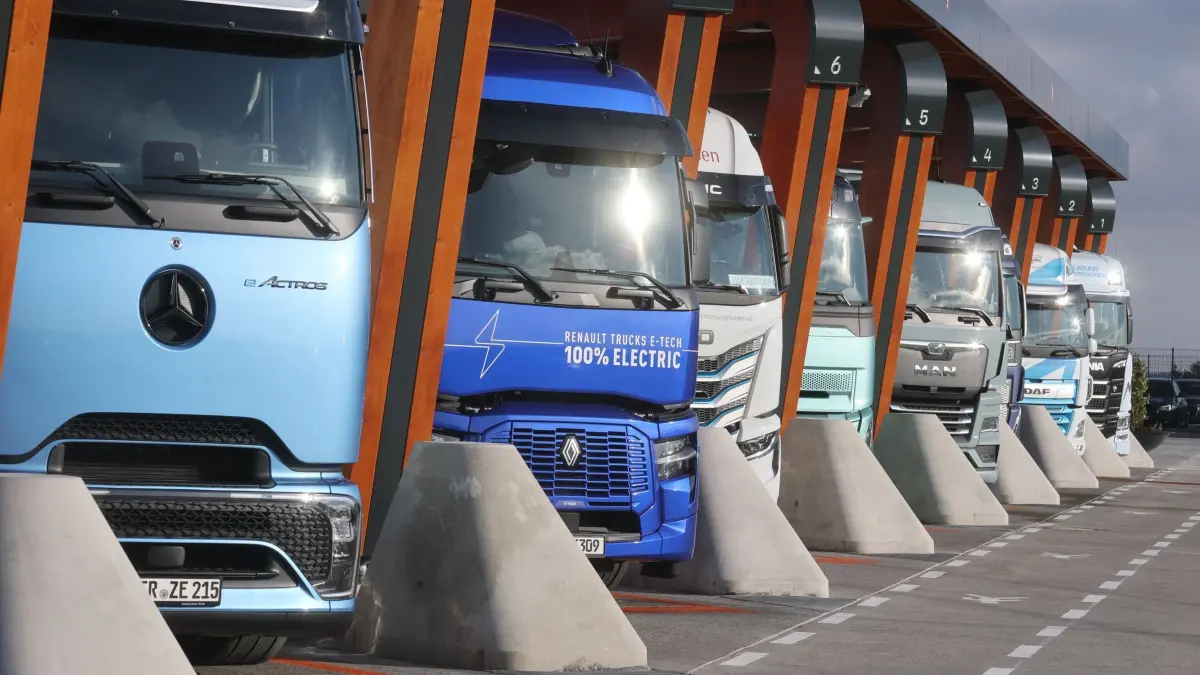 Thüringer Verkehrsgewerbe fordert Lockerung bei Arbeitszeit: ARCHIV - 05.12.2024, Thüringen, Kraftsdorf: Lkw mit Elektroantrieb stehen in einer Ladebox bei der Einweihung eines Ladeparks für E-Lastwagen am Hermsdorfer Kreuz. Es brauche eine Ausnahme für das Verkehrsgewerbe, um die maximal erlaubte Tagesarbeitszeit im Bedarfsfall überschreiten zu dürfen, so Martin Kammer, Hauptgeschäftsführer des Landesverbandes Thüringen des Verkehrsgewerbes. (Symbolbild) (zu dpa: «Logistikunternehmer fordern Lockerung bei Höchstarbeitszeit») Foto: Bodo Schackow/dpa +++ dpa-Bildfunk +++