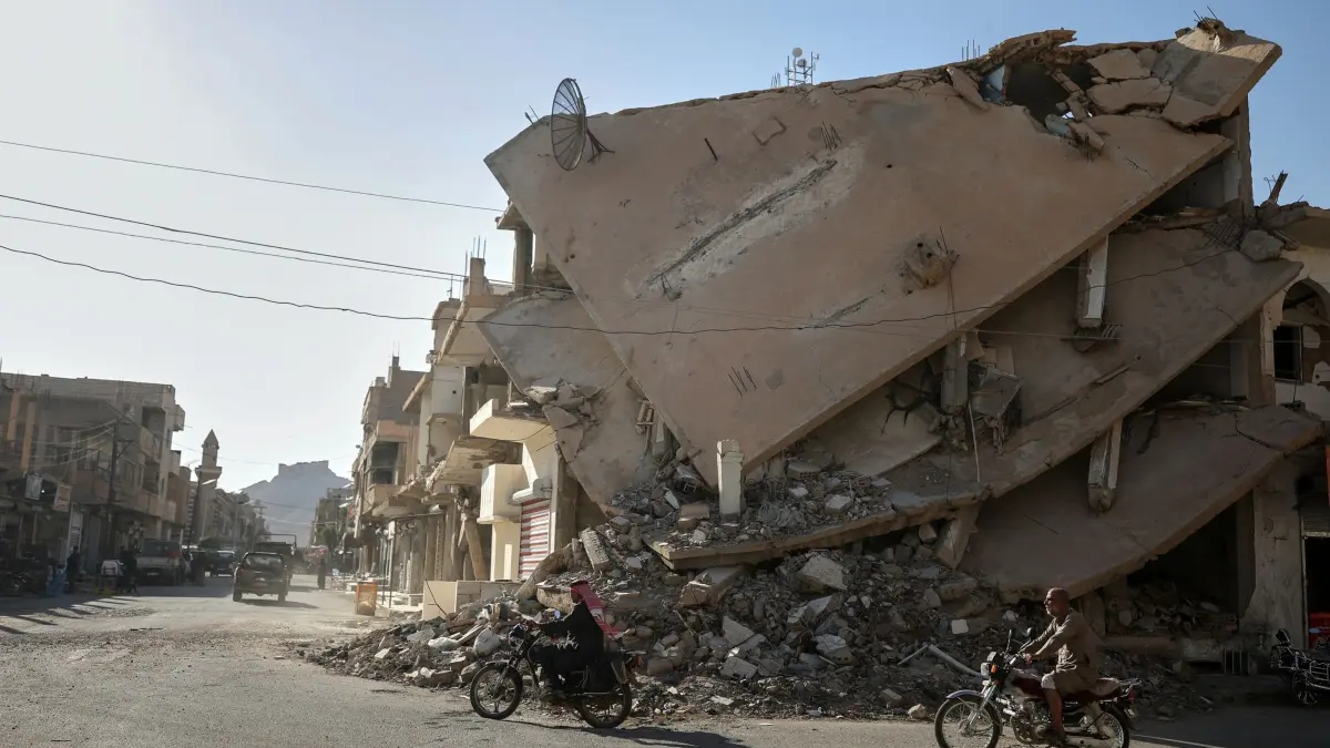 Oasenstdt Palmyra: 26.08.2025, Syrien, Palmyra: Anwohner fahren auf einem Motorrad durch eine vom Krieg zerstörte Straße der Oasenstadt. Foto: Ghaith Alsayed/AP/dpa +++ dpa-Bildfunk +++