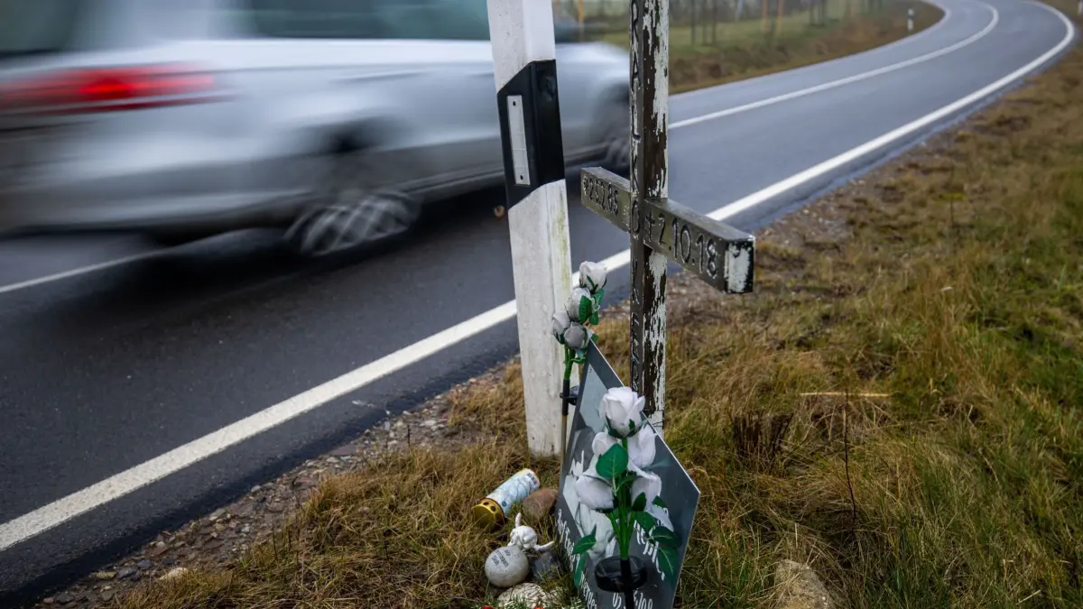 Symbolbild zu Verkehrsunfällen auf Landstraßen: ARCHIV - 28.02.2025, Mecklenburg-Vorpommern, Dorf Mecklenburg: Ein Auto fährt auf einer Landstraße an einem hölzernen Kreuz vorbei, welches zur Erinnerung an ein Unfallopfer aufgestellt wurde. (Aufnahme mit langer Belichtungszeit). (zu dpa: «Autofahrerin stirbt bei Unfall in Ganderkesee») Foto: Jens Büttner/dpa +++ dpa-Bildfunk +++