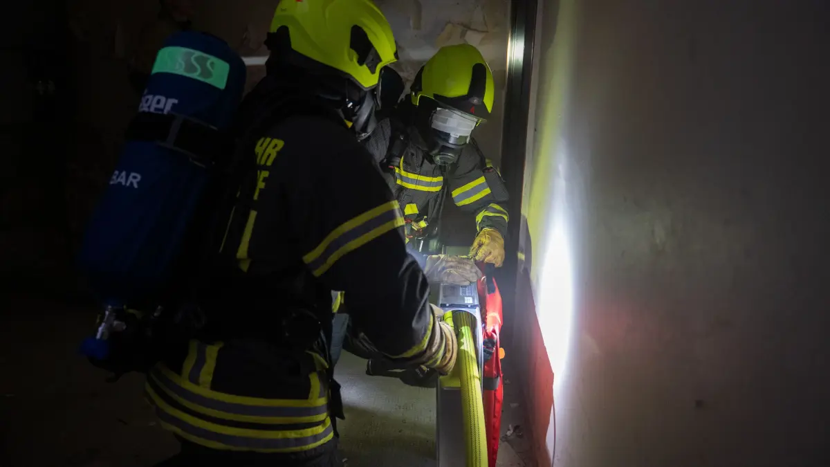 Ein Angriffstrupp der Freiwilligen Feuerwehr Woltersdorf im Keller des Gebäudes. Sie sollen den fiktiven Brand löschen. Um ihre Sicht einzuschränken – wie es bei Bränden durch den Rauch geschieht – wurden die Atemschutzmasken abgeklebt.