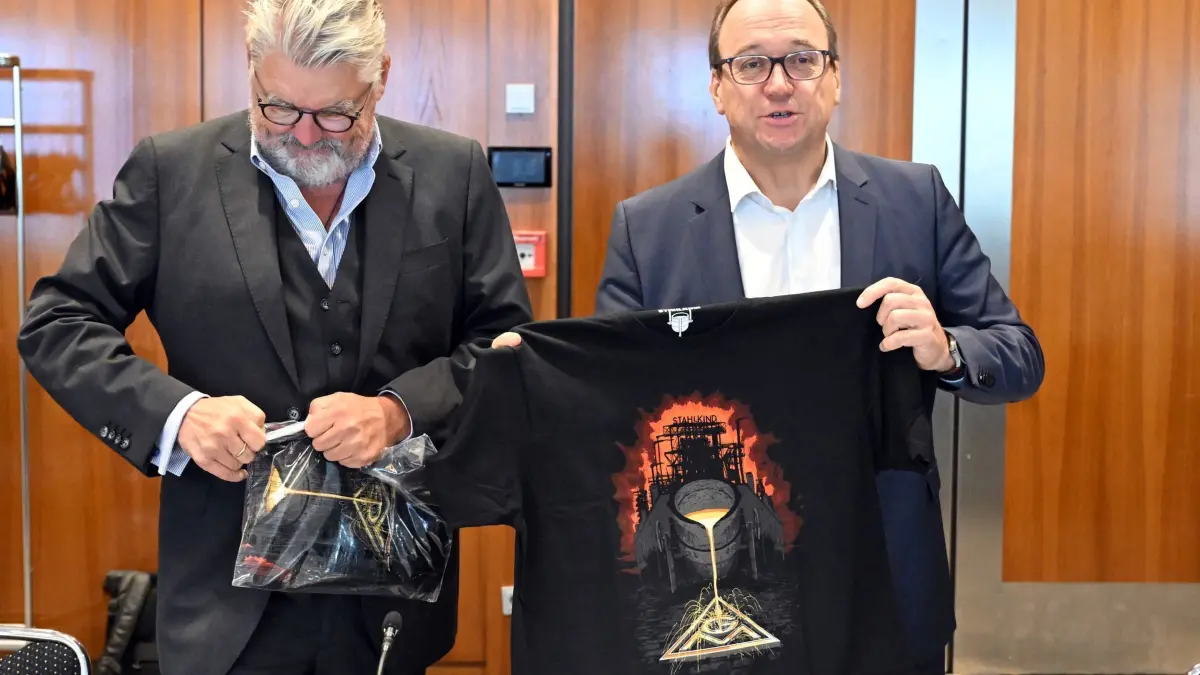 Tarifverhandlungen für die Stahlindustrie beginnen: 16.09.2025, Nordrhein-Westfalen, Düsseldorf: Reiner Blaschek (r), Vorsitzender des Arbeitgeberverbandes Stahl, hält vor Beginn der Verhandlungen ein IG Metall-T-Shirt in den Händen. Die Tarifverhandlungen für die Stahlindustrie beginnen, Die Tarifverhandlungen betreffen zunächst die Gebiete «Nordwest» und «Ost», wo allein 68.000 Beschäftigte betroffen sind. Foto: Federico Gambarini/dpa +++ dpa-Bildfunk +++