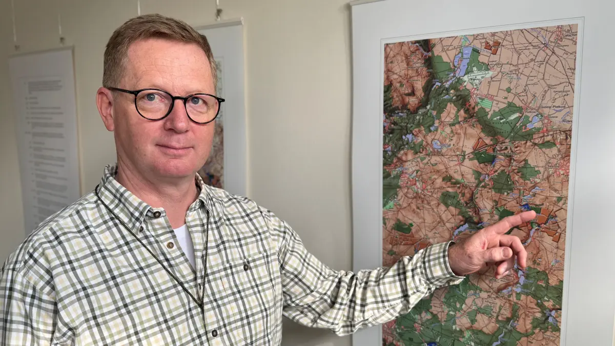 Felix Gerlach, Geschäftsführer der Komturei Lietzen GmbH, zeigt auf der Karte die Lage der Ackerflächen, auf der seit 30 Jahren geforscht wird.