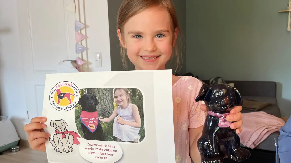 Charlotte Ludwig hält ein Foto ihres Reha-Begleithundes ins Bild und einen selbst bemalten Porzellanhund, der dem zukünftigen Therapiehund ähnelt. Bitte das Bild nur im Zusammenhang mit der Berichterstattung über den Therapiehund und diese Familie verwenden. Einverständniserklärung der Eltern liegt vor.