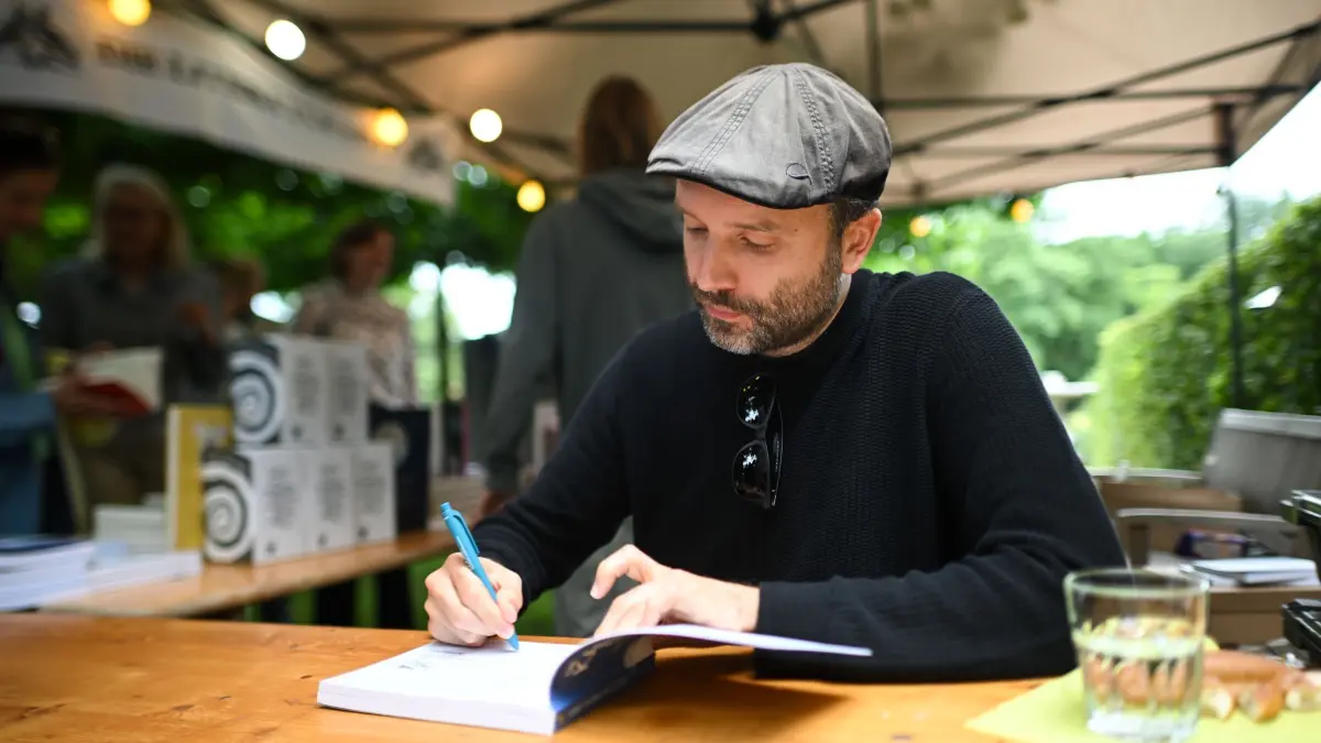 Potsdamer Literaturfestival „LIT:potsdam“ - Marc-Uwe Kling: ARCHIV - 05.07.2024, Brandenburg, Potsdam: Autor Marc-Uwe Kling signiert während des Potsdamer Literaturfestivals "LIT:potsdam" im Park der Villa Jacobs Bücher. Motto des Festivals vom 02.07. bis 07.07.2024 ist "Vorwärts zur Natur". (zu dpa: «Bestseller-Autor Kling: Erster Soloauftritt war Ein-Euro-Job») Foto: Sebastian Gollnow/dpa +++ dpa-Bildfunk +++