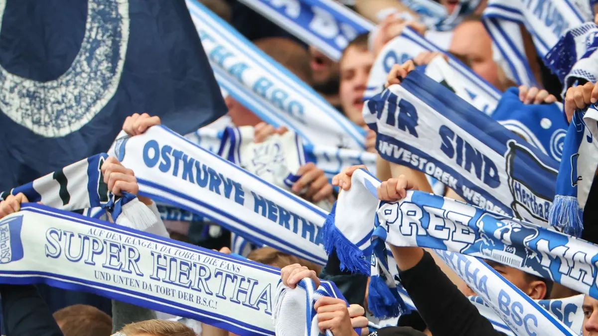 1. FC Nürnberg - Hertha BSC: 28.09.2025, Bayern, Nürnberg: Fußball, 2. Bundesliga, 1. FC Nürnberg - Hertha BSC, 7. Spieltag im Max-Morlock-Stadion. Fans von Hertha BSC singen während des Spielverlaufs und halten ihre Fan-Schals. Foto: Daniel Karmann/dpa - WICHTIGER HINWEIS: Gemäß den Vorgaben der DFL Deutsche Fußball Liga bzw. des DFB Deutscher Fußball-Bund ist es untersagt, in dem Stadion und/oder vom Spiel angefertigte Fotoaufnahmen in Form von Sequenzbildern und/oder videoähnlichen Fotostrecken zu verwerten bzw. verwerten zu lassen. +++ dpa-Bildfunk +++