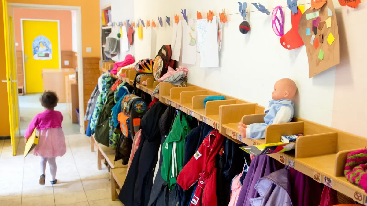 ARCHIV - Ein Mädchen geht am 12.05.2014 in einer Kindertagesstätte in Stuttgart (Baden-Württemberg) an einem Garderobenständer vorbei. Foto: Sebastian Kahnert/dpa (zu lsw: «Ein Jahr Rechtsanspruch auf Kita-Plätze für Kleinkinder - kaum Klagen» vom 30.07.2014) +++ dpa-Bildfunk +++