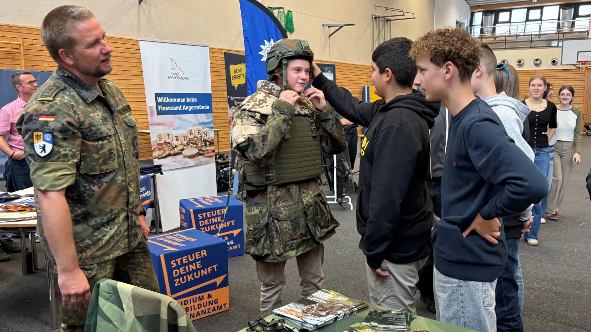 Für den Dienst in Uniform wirbt die Bundeswehr aktiv bei der Berufe- und Ausbildungsmesse für Schulen in Angermünde. Anziehprobe gehört dazu. Björn Mosebach (l), Karriereberater bei der Bundeswehr, stellt sich den Fragen der Jugendlichen.